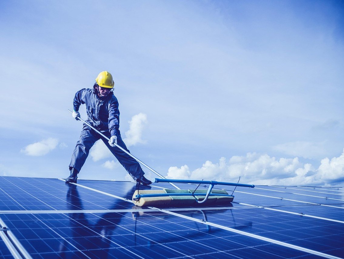 Engineer cleaning and inspecting solar panels